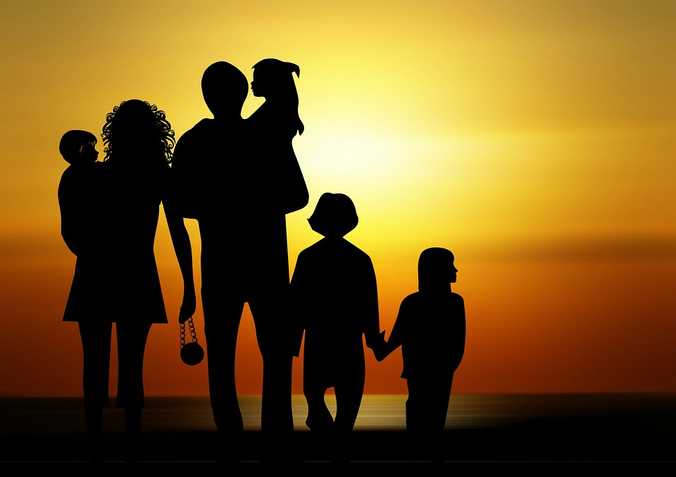 Logo przedstawia tradycyjną rodzinę: kobietę i mężczyznę na tle zachodzącego słońca na plaży, którzy niosą na rękach małe dzieci oraz idące obok dzieci, trzymające się za ręce. Grafika - max pixel na licencji creative commons